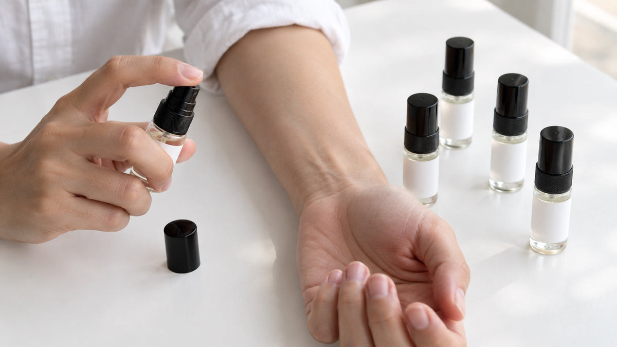 Fotografia ilustracyjna: wybór próbki z zestawu i przygotowanie testu perfum na skórze.