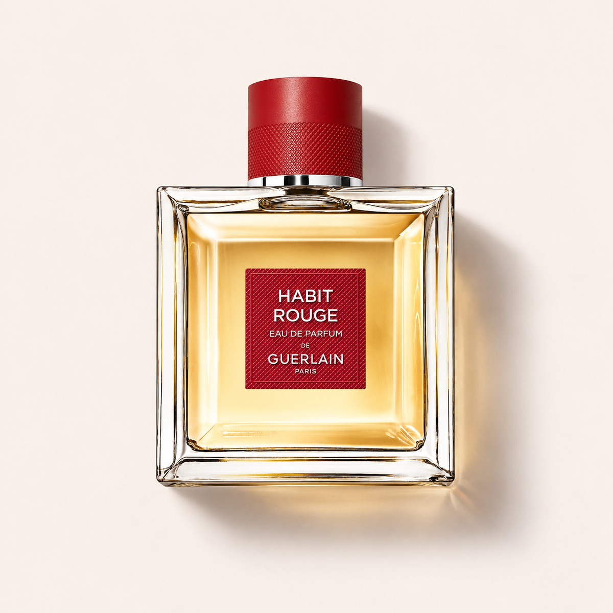 Flakon Guerlain Habit Rouge EDP 100 ml na béžovém pozadí – MrRizz