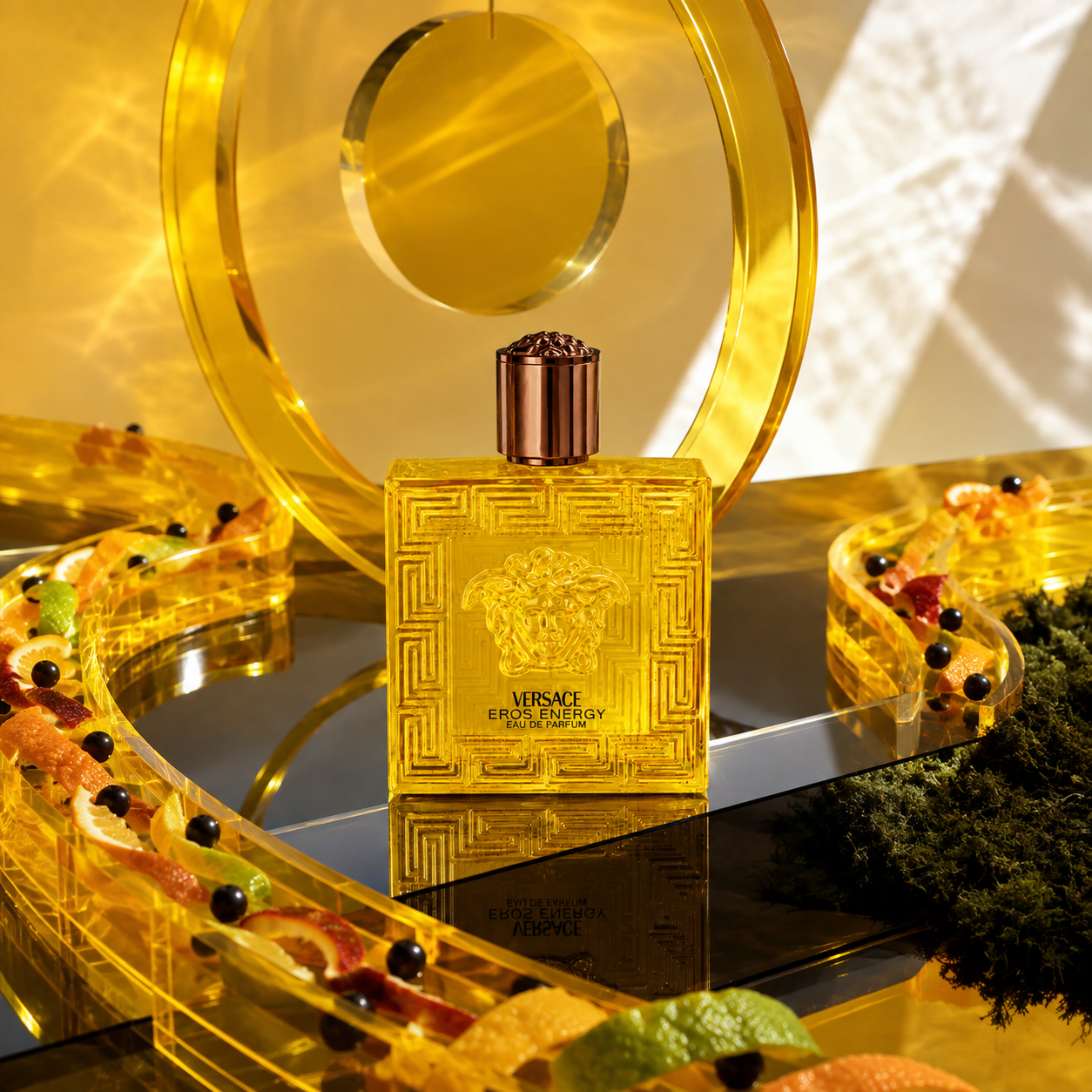 Versace Eros Energy ve žlutém skleněném zátiší s citrusovou kůrou, černými bobulemi a mechem – MrRizz